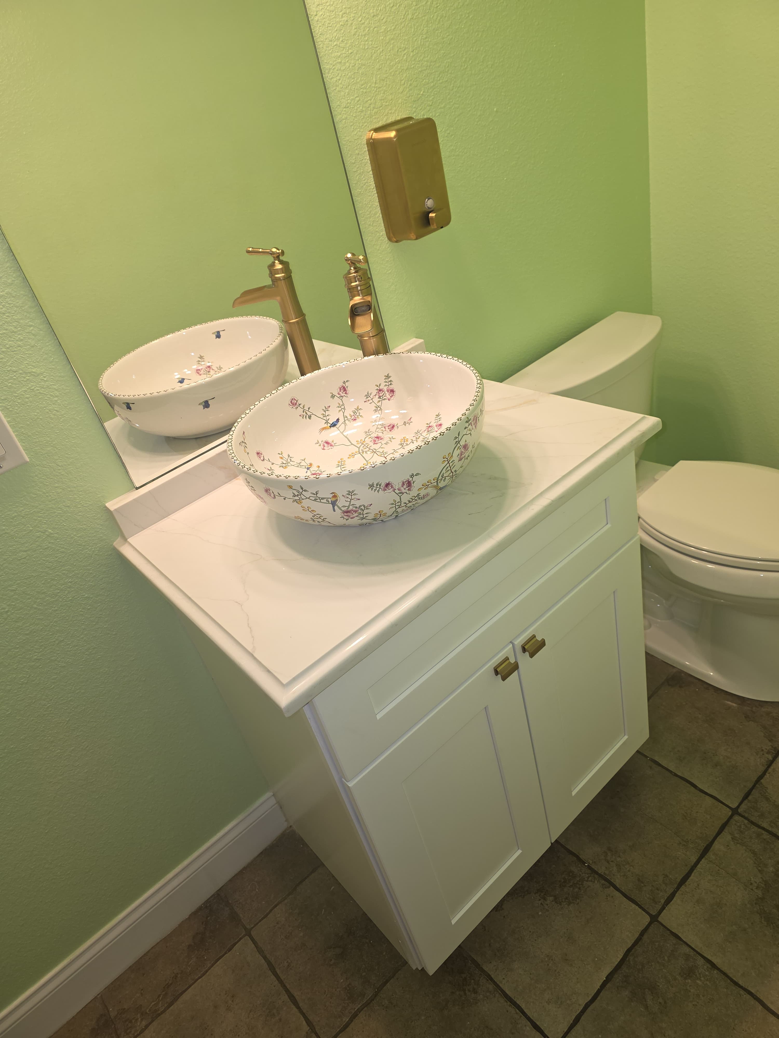 White vanity with decorative floral vessel sink and gold faucet