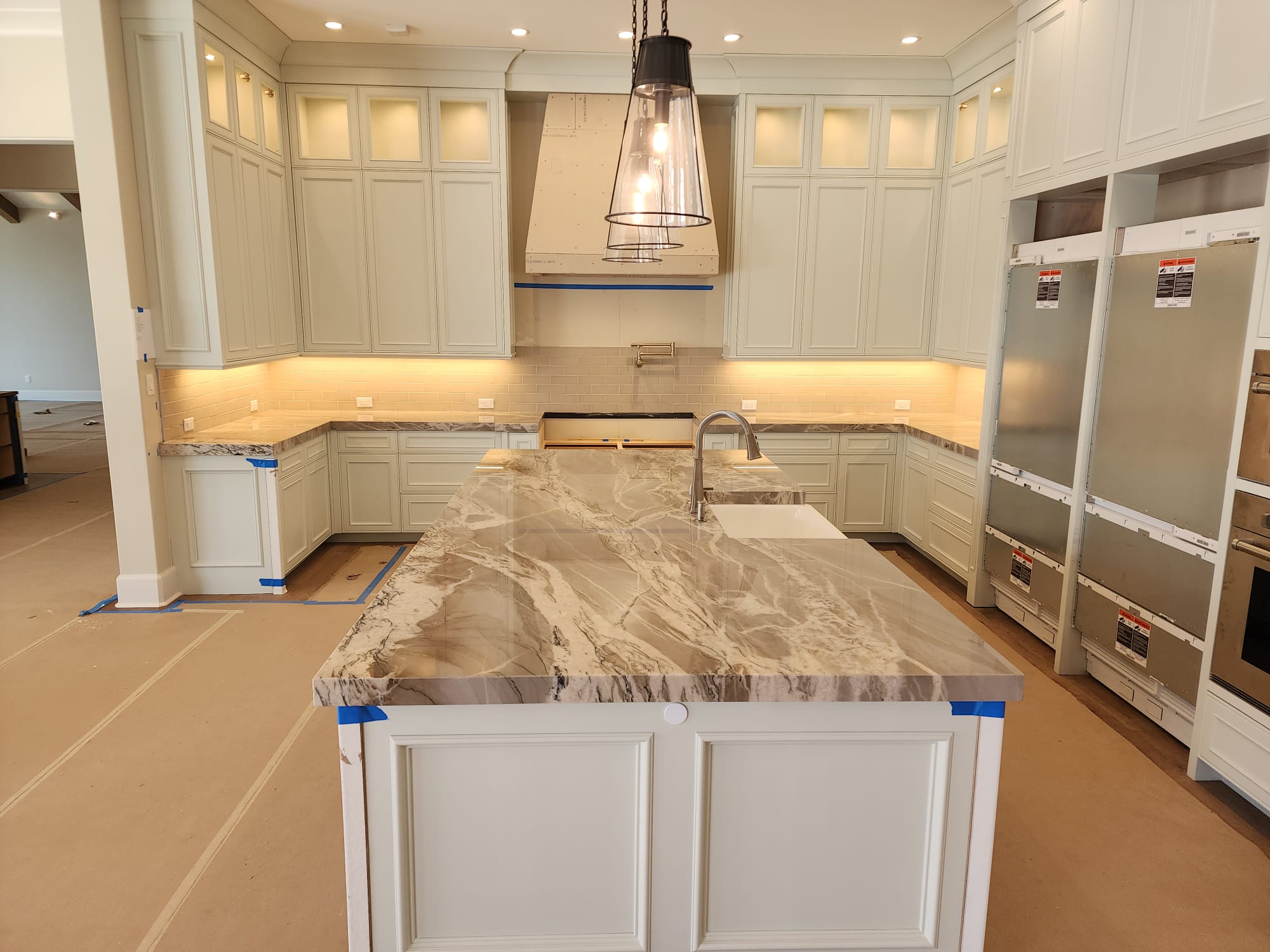 Large marble kitchen island with waterfall edge being installed in luxury kitchen